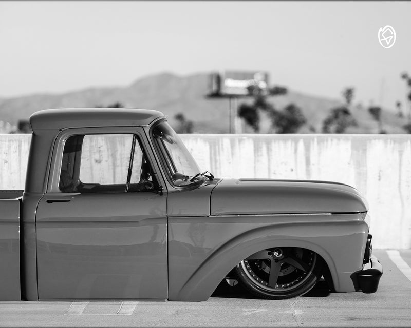 Vintage turquoise and orange car on a road with trees in the background - Greasy Hands Society Lifestyle