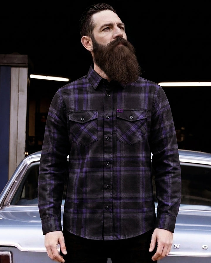Man wearing a black and purple plaid flannel shirt standing in front of a car - Kiss the Sky Flannel by Greasy Hands Society