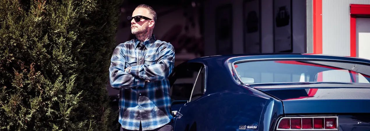 a man standing outside with a blue classic car wearing sunglasses and a blue, white and black plaid flannel shirt - The Nailhead Flannel by Greasy Hands Society