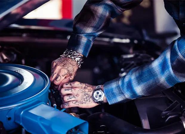 a man working on a car engine wearing a flannel shirt - The Cold Start Flannel by Greasy Hands Society