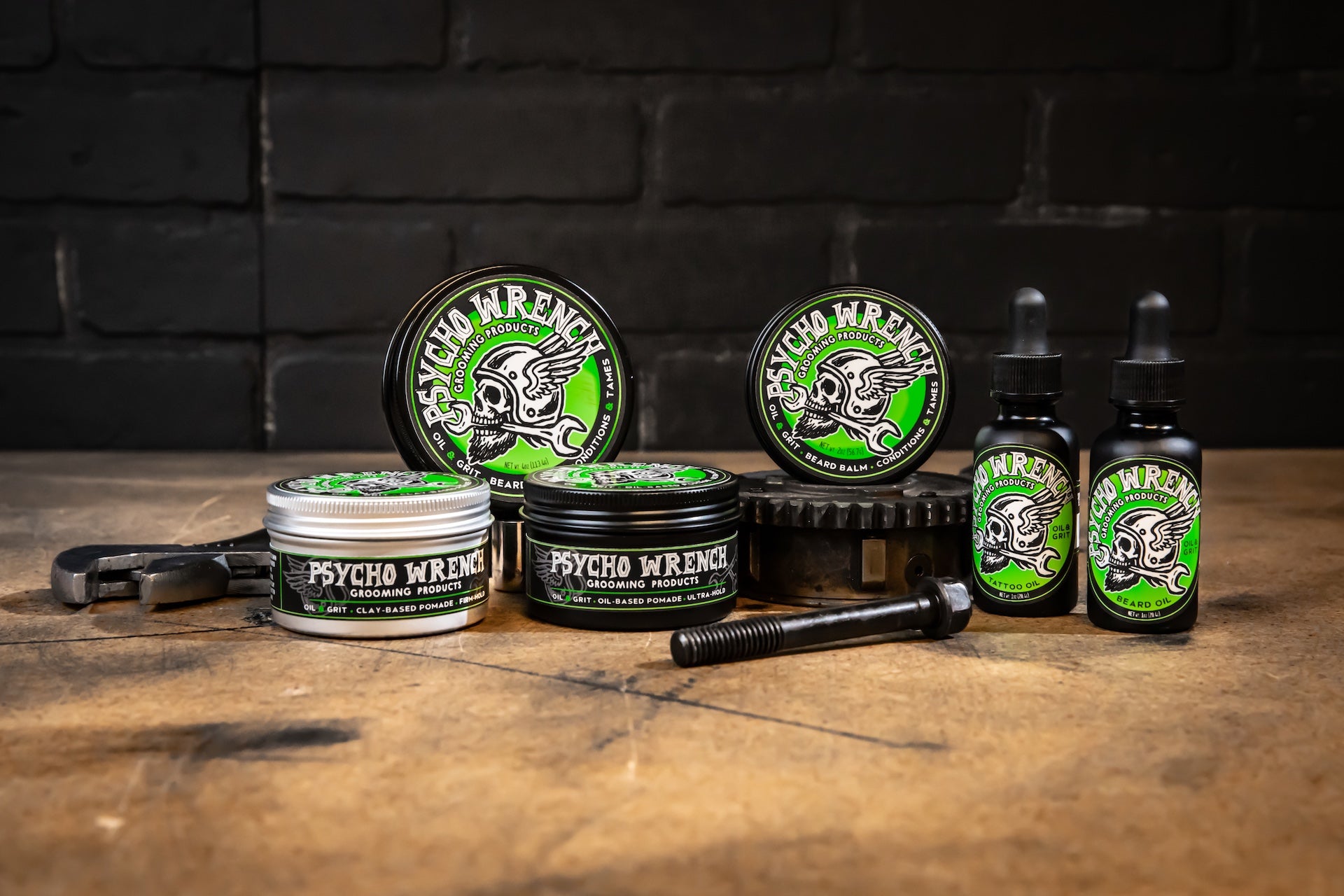 Collection of Psycho Wrench products including jars and bottles on a wooden surface with a dark brick wall background.