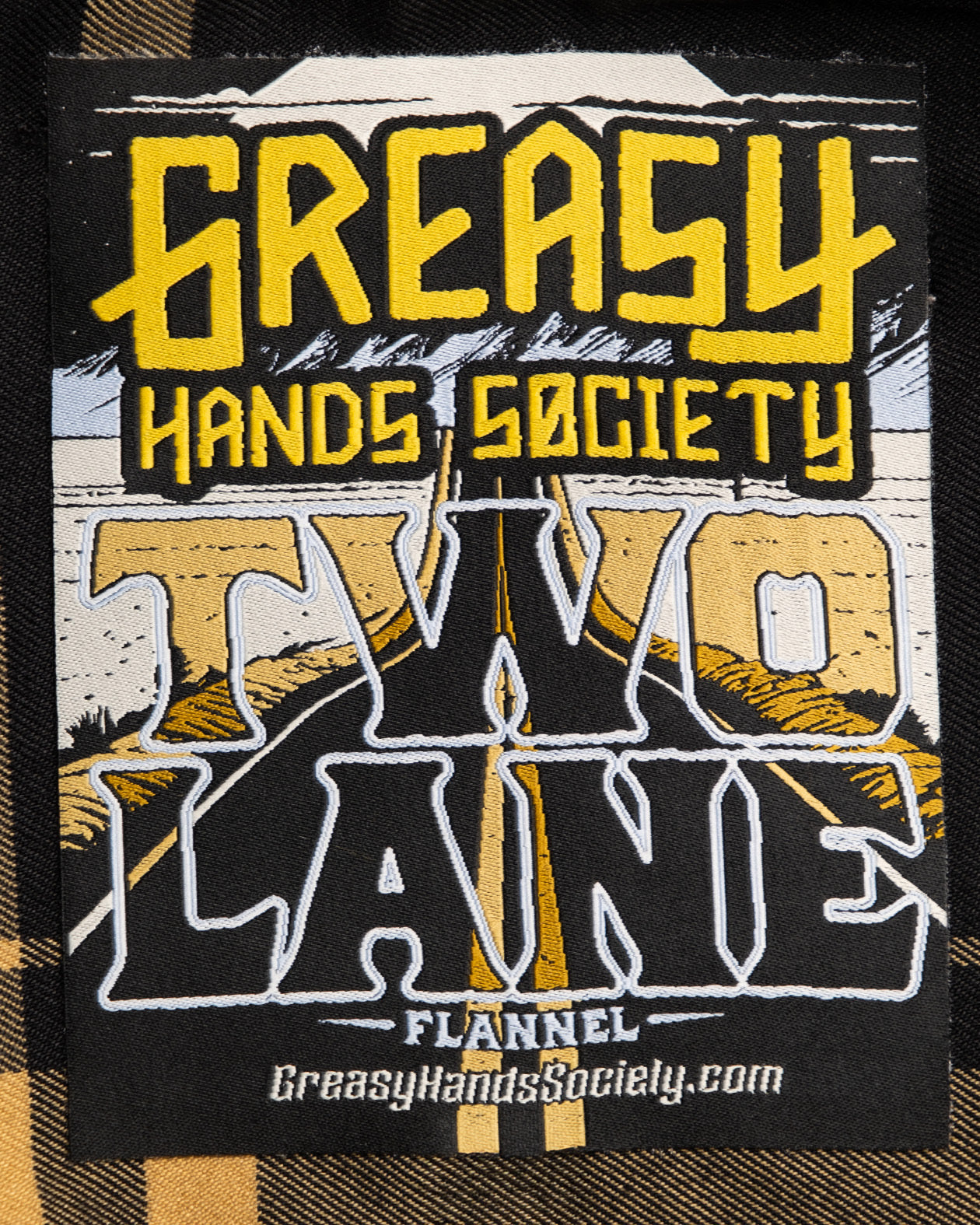 tag label art showing a two-lane highway for the two lane black and gold flannel