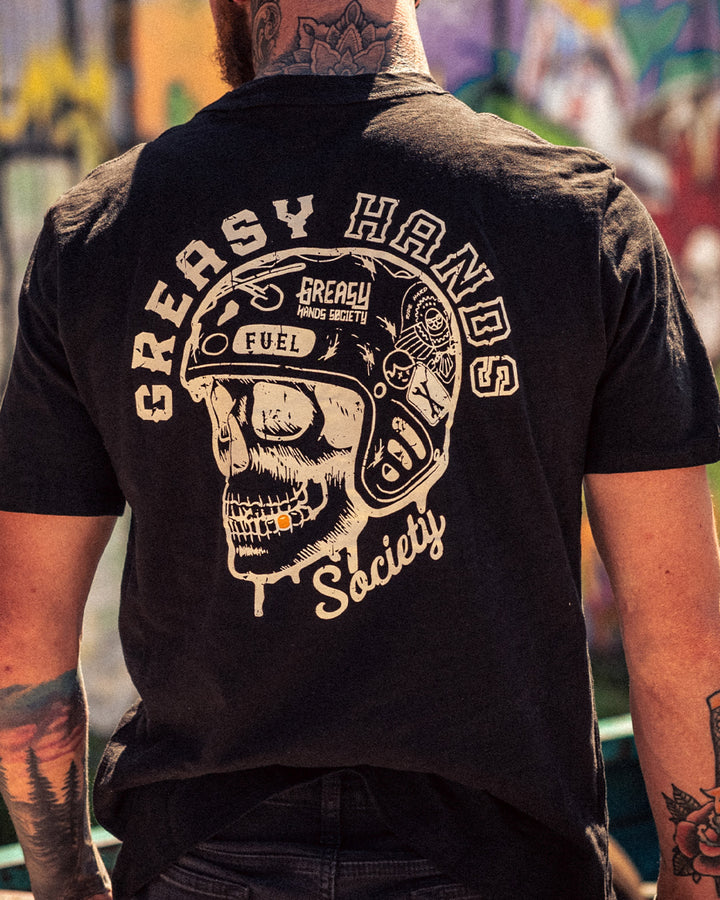 Person wearing a black t-shirt with 'Greasy Hands Society' graphic on the back, standing in an urban setting - Men's Drippin' black graphic tee by Greasy Hands Society