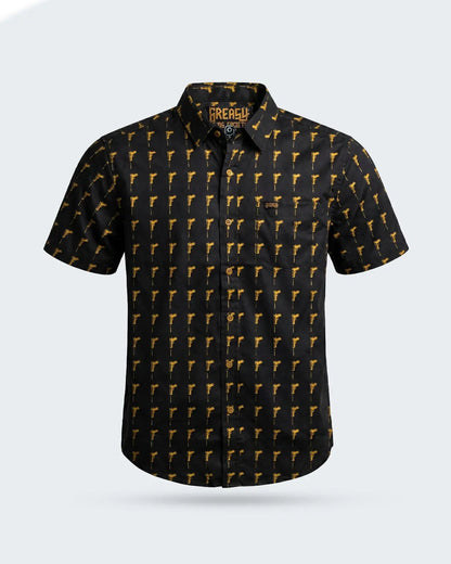 A short-sleeve button-up shirt by The Rebel, featuring a black base with a repeating yellow pistol pattern, displayed on a light gray background - The Hitman Button-Up Shirt by Greasy Hands Society