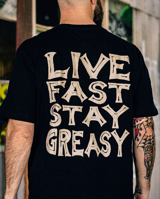 Person wearing a black t-shirt with 'Live Fast Stay Greasy' text on the back - Live Fast Graphic Tee from Greasy Hands Society