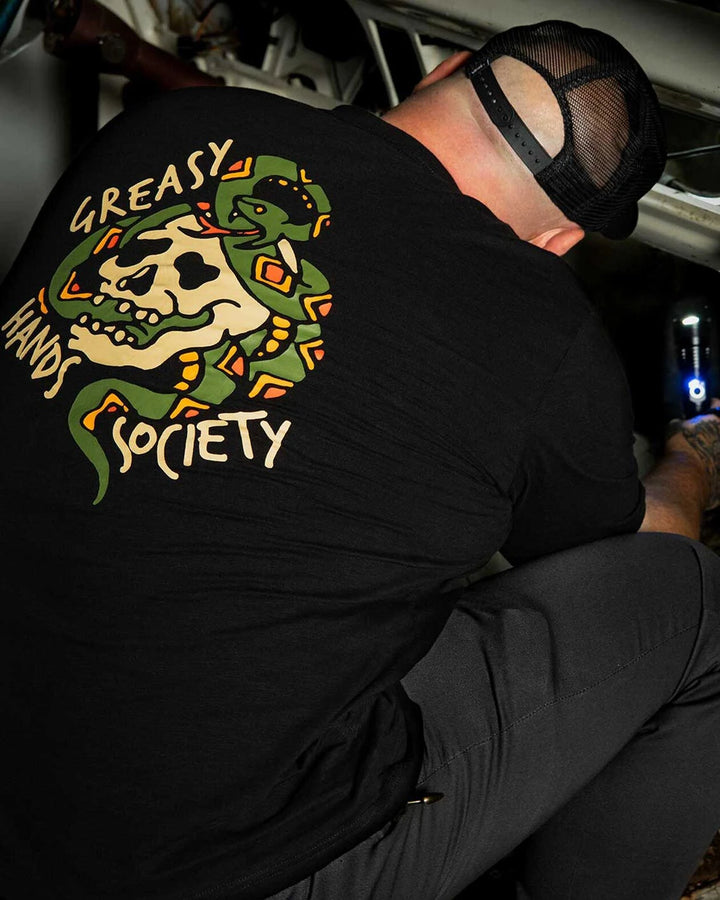 Person wearing a black t-shirt with a graphic design and text, sitting inside a vehicle - Pressure Graphic Tee by greasy hands society