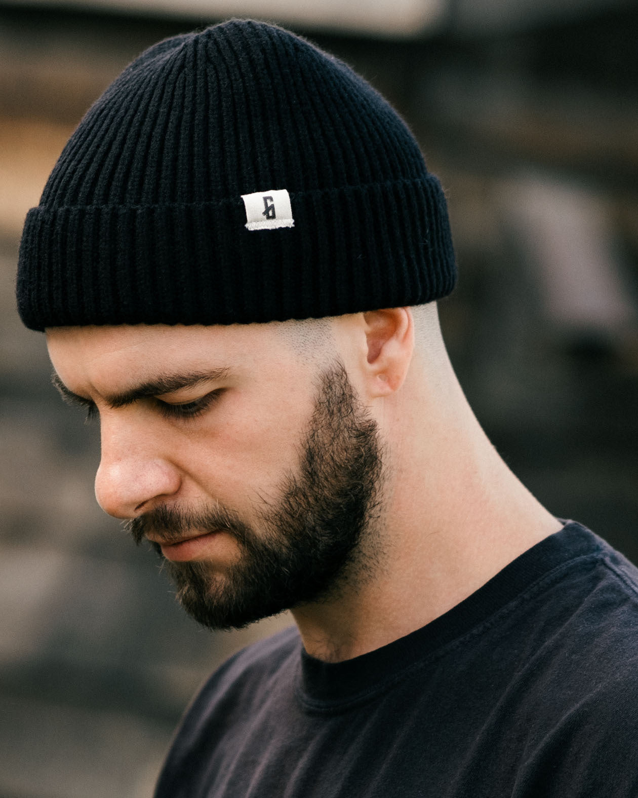 black watch cap with greasy hands society icon "G" on the tag being worn by a model